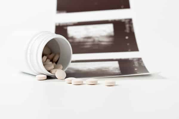 pills spilling from bottle in front of ultrasound image