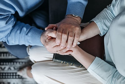 Two women's hands clasped in prayer